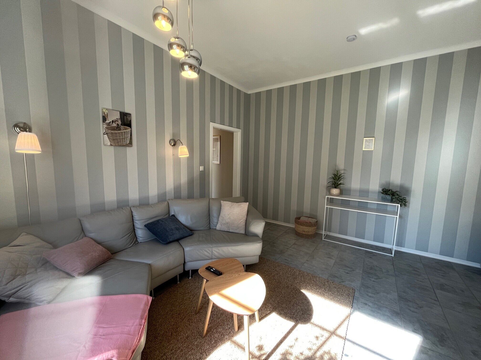 A living room with a sofa, a coffee table, a lamp, and a striped wall.