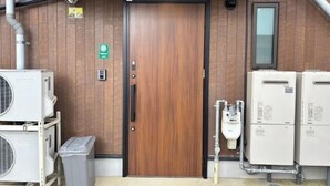 A room with a wooden door, air conditioning units, and a trash bin. - Private Villa Tofukuji (Kyoto)