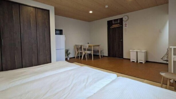 A bedroom with a bed, a wooden ceiling, a small table with chairs, and a wardrobe. - Private Villa Tofukuji (Kyoto)