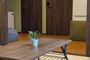 Ein Zimmer mit Holztisch, Topfpflanze, Sofa und Tür.