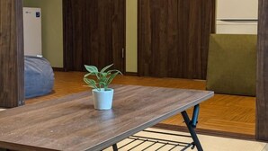 A room with a wooden floor, a bed, a table with a plant, and wooden doors. - Private Villa Tofukuji (Kyoto)
