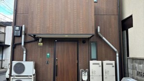 A modern building with a wooden facade, a central entrance, and air conditioning units on the ground floor. - Private Villa Tofukuji (Kyoto)