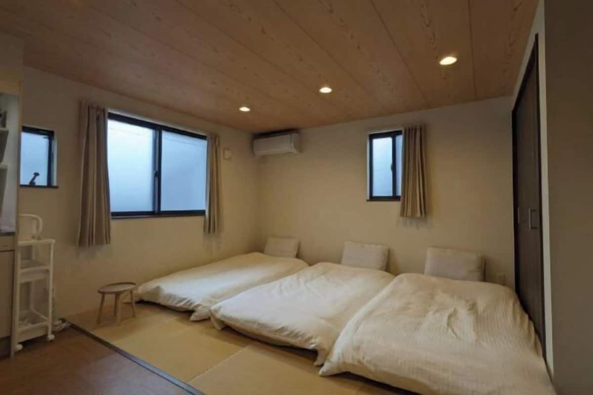 Een kamer met twee bedden, een tafeltje, een stoel en een raam.