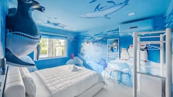 Una habitación con una cama, literas y un mural de vida marina.