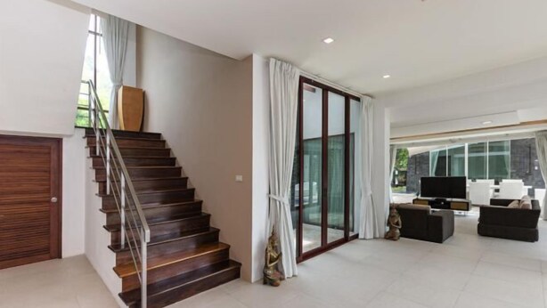 Un salon moderne avec un escalier, une porte vitrée et un téléviseur à écran plat.