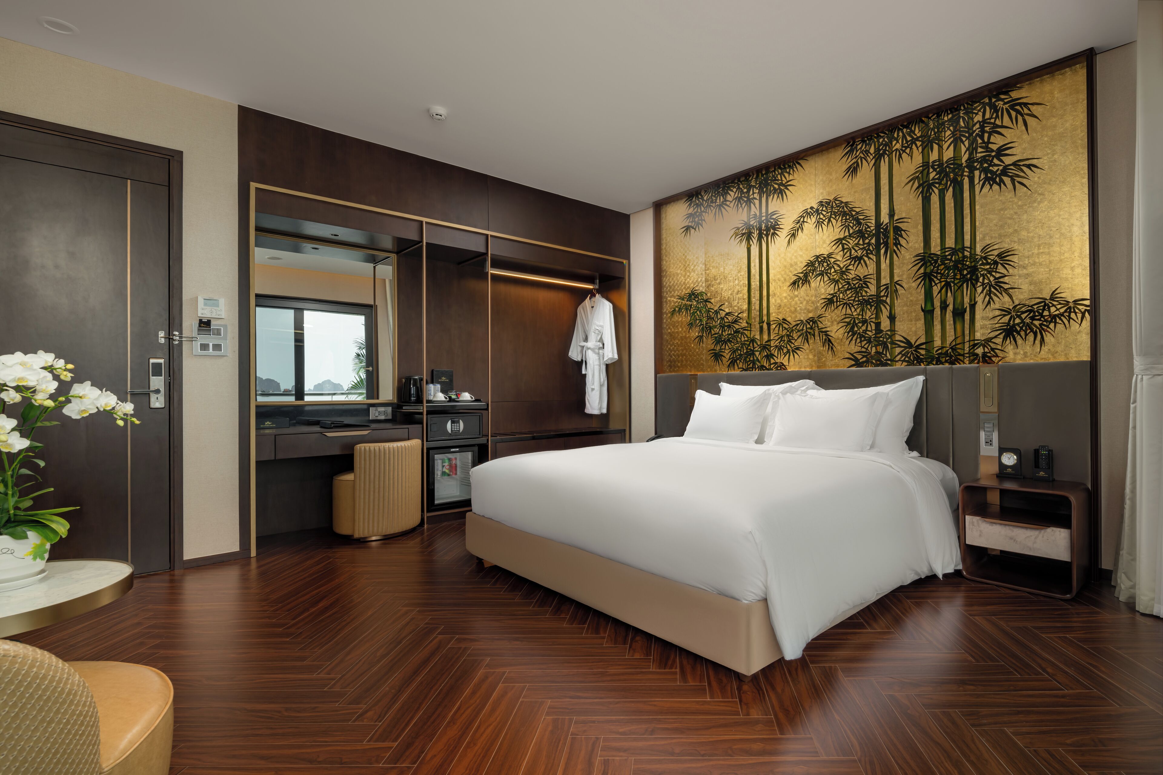 A modern hotel room with a large bed, a walk-in closet, a bathroom, and a wall with a bamboo mural.