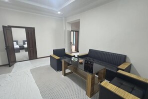 A modern living room with a sofa, a coffee table, and a mirror. - Bmb Village Jizzakh Hotel (Jizzakh)