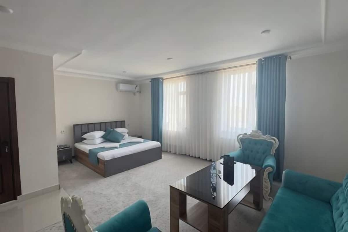 Una habitación de hotel con cama, escritorio, silla y ventana con cortinas.