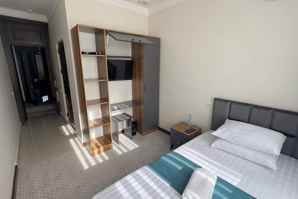 Una habitación de hotel con una cama, un armario, una mesita de noche y una puerta que da a otra habitación.