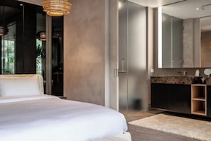 Un dormitorio moderno con una cama grande, un vestidor y un baño con un espejo amplio.
