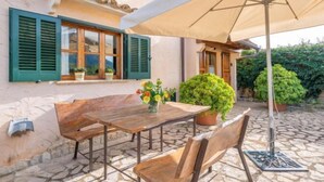 An outdoor patio with a wooden table and chairs, a beige umbrella, and potted plants. - REYNES - Rustic villa with private pool and free Wi-Fi (Pollensa)