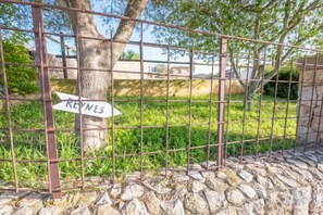 A metal fence with a sign reading 'REYNES' in front of a stone wall and a grassy area. - REYNES - Rustic villa with private pool and free Wi-Fi (Pollensa)