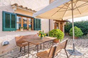 An outdoor patio with a wooden table and chairs, a potted plant, and a large umbrella. - REYNES - Rustic villa with private pool and free Wi-Fi (Pollensa)