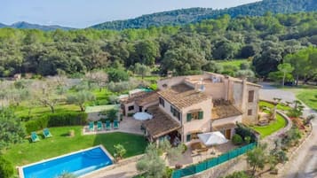 A villa with a swimming pool, surrounded by lush greenery and hills.