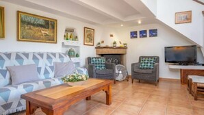 A living room with a sofa, a wooden coffee table, two armchairs, a television, and a fireplace. - REYNES - Rustic villa with private pool and free Wi-Fi (Pollensa)