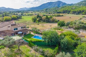 A house with a swimming pool, surrounded by lush greenery and mountains in the background. - REYNES - Rustic villa with private pool and free Wi-Fi (Pollensa)