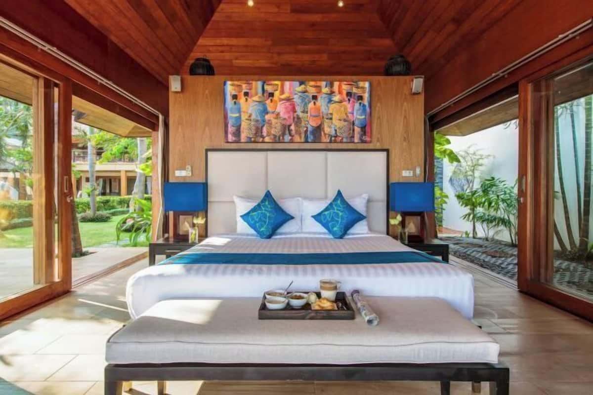 Un dormitorio con una cama grande, dos almohadas, una bandeja con comida y un cuadro sobre la cama.