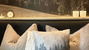 Quarto com vista para montanhas, uma cama com edredom branco e duas mesas de cabeceira com velas.