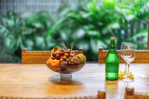 Ein Holztisch mit Obstschale, einer Flasche und zwei Gläsern.