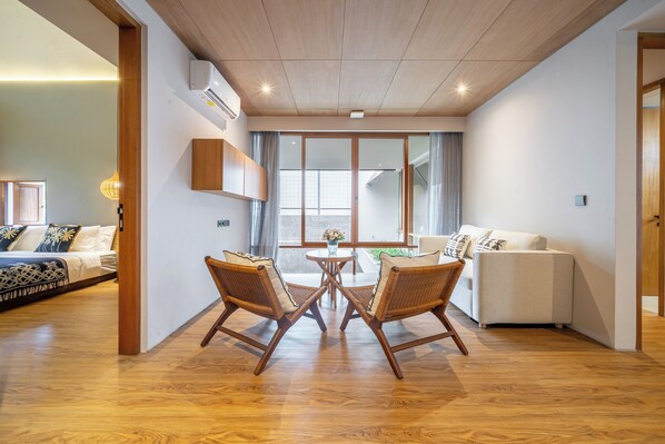 Un salon moderne avec un plancher en bois, un canapé, une table à manger avec des chaises et une grande fenêtre avec des rideaux.