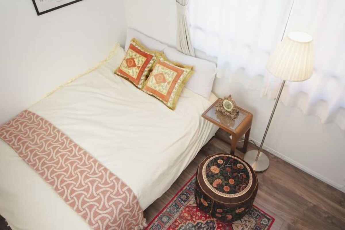A neatly made bed with patterned bedding, a small bedside table with a lamp, and a decorative rug.