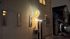 A building with a sign indicating a restaurant or cafe. There are two doors, one with a light above it. The building has a brick facade with windows and a door. - QiQi House Serenity~Private Near Asakusa & Skytree (Tokyo)