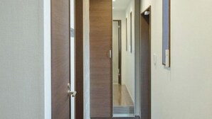 A hallway with a wooden door, a wooden wall, and a light switch on the wall. - QiQi House Serenity~Private Near Asakusa & Skytree (Tokyo)