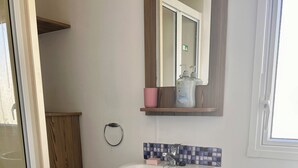A bathroom with a white sink, a toilet, and a shower area. - Spacious Holiday Home in Exmouth Ocean V (Exmouth)