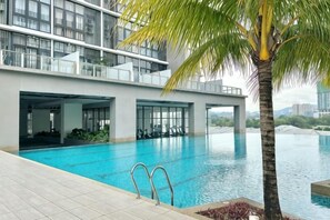 A modern building with a swimming pool, a palm tree, and a view of the city. - Modern Comfy Bdr Permaisuri 2 parking WIFI Netflix (Kuala Lumpur)
