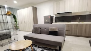 A modern living room with a grey sofa, a small wooden table, and a black and white furry rug. - Modern Comfy Bdr Permaisuri 2 parking WIFI Netflix (Kuala Lumpur)