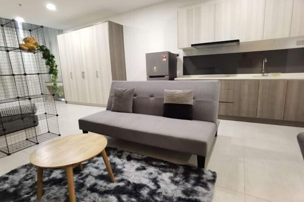 A modern living room with a grey sofa, a small wooden table, and a black and white furry rug.