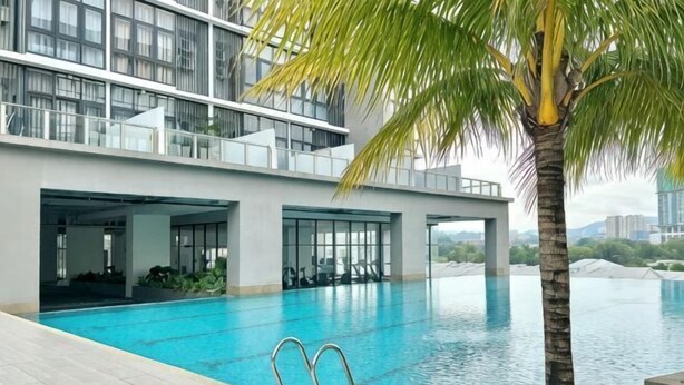 A modern hotel with a swimming pool, a palm tree, and a view of the city. - Modern Comfy Bdr Permaisuri 2 parking WIFI Netflix (Kuala Lumpur)