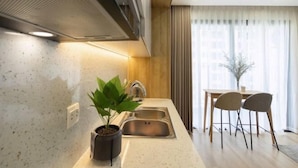Una cocina moderna con estufa integrada, un lavaplatos y un comedor con dos sillas y una mesa.