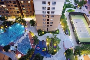 Edifici residencial de diverses plantes amb piscina, pista de tennis i zones enjardinades.
