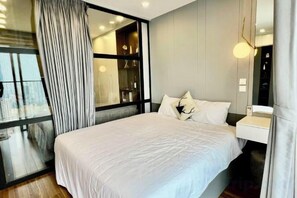 A modern hotel room with a large bed, a bedside table, and a view through a glass door. - HaChu House (Hanoi)