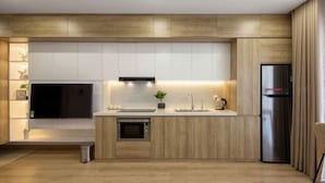 Una cocina moderna con armarios de madera, horno empotrado, refrigerador de acero inoxidable y un ventanal sobre el fregadero.
