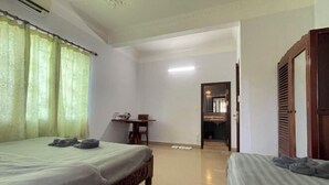 A hotel room with two beds, a small table with a chair, and a door leading to another room. - Le-nou Siemreap Guesthouse (Siem Reap)