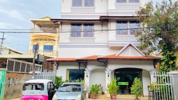 A multi-story building with a traditional architectural style, featuring a prominent entrance with a decorative archway and potted plants. - Le-nou Siemreap Guesthouse (Siem Reap)