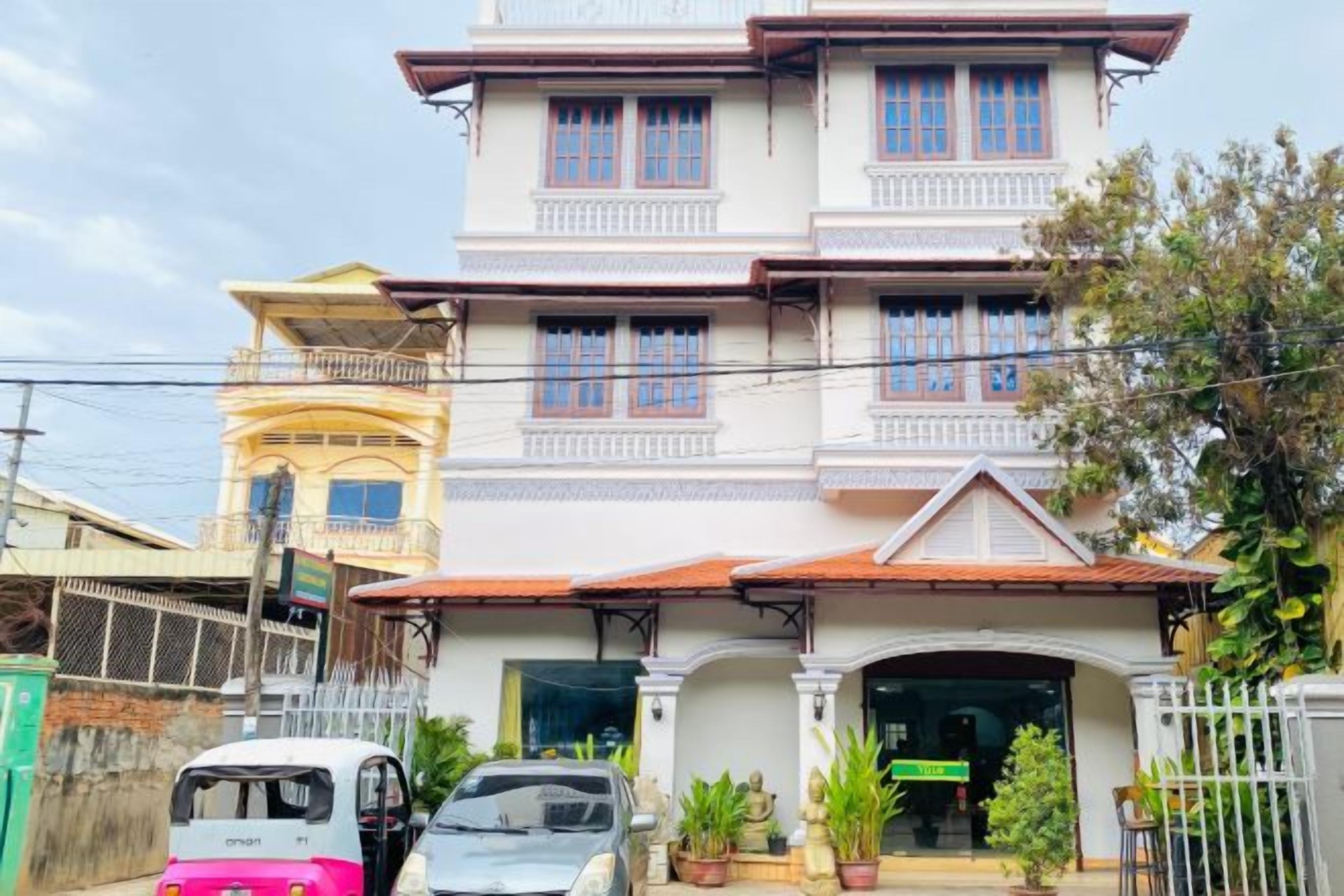 A multi-story building with a traditional architectural style, featuring a balcony on the upper floor and a gated entrance.