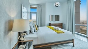 Une chambre d’hôtel moderne avec un grand lit, une table de chevet avec une lampe, une vue par la fenêtre et un luminaire suspendu.