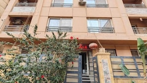 Un immeuble à plusieurs étages doté de balcons, d’une entrée principale et d’une grille décorative.