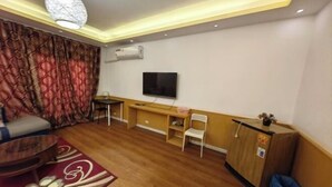 Un salon comprenant un canapé, un téléviseur, un meuble en bois et un tapis à motifs.