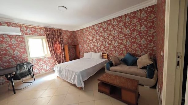 Une chambre à coucher avec un lit, un canapé, un bureau et une chaise.