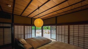 A traditional Japanese-style room with tatami flooring, a low ceiling with wooden beams, a hanging paper lantern, and shoji screens. - Takeda Base Inn (Asago)