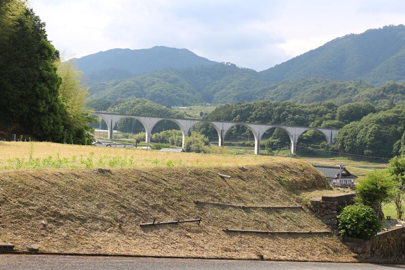 A bridge over a river, surrounded by hills and greenery.