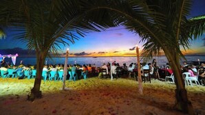 A beachside gathering with people seated at tables under palm trees, overlooking the sea. - Carabao Island Beach Camp (San Jose)