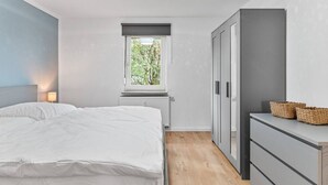 A bedroom with a bed, a window, a radiator, a wardrobe, and a desk with baskets. - Work & Stay - Apartment with office (Leinfelden-Echterdingen)