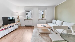 A modern living room with a TV, wooden entertainment unit, sofa, and a coffee table. - Work & Stay - Apartment with office (Leinfelden-Echterdingen)