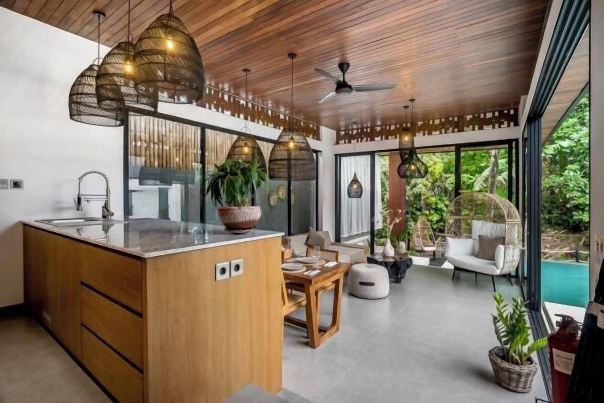 A modern kitchen with a central island, wooden cabinets, and pendant lighting.