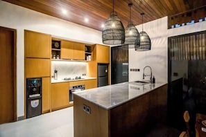 Eine moderne Küche mit Holzschränken, einer Marmorarbeitsplatte und Pendelleuchten.